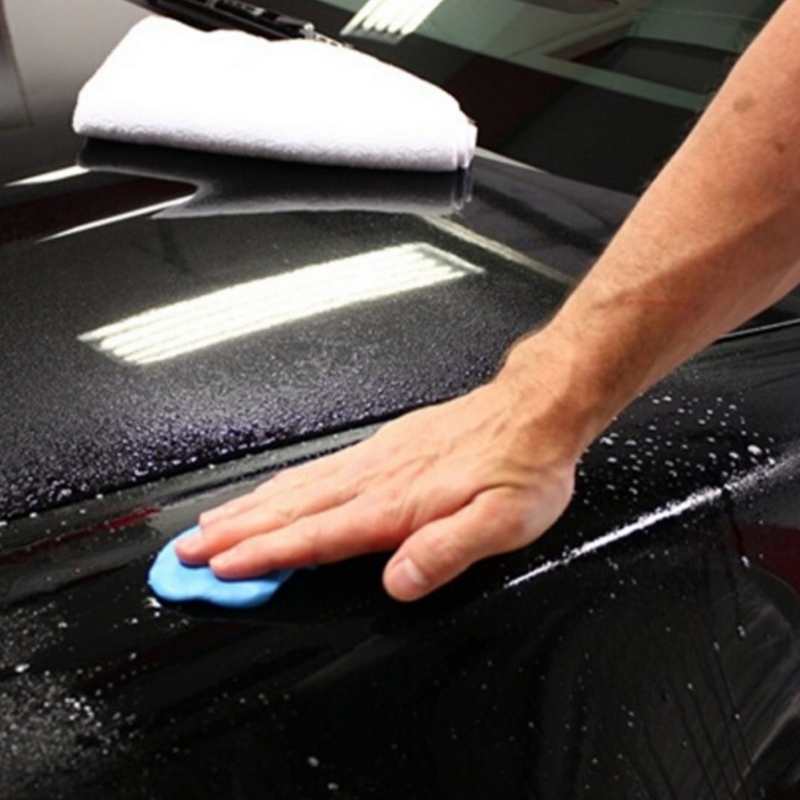 Mobile car detailing technician applying clay bar treatment